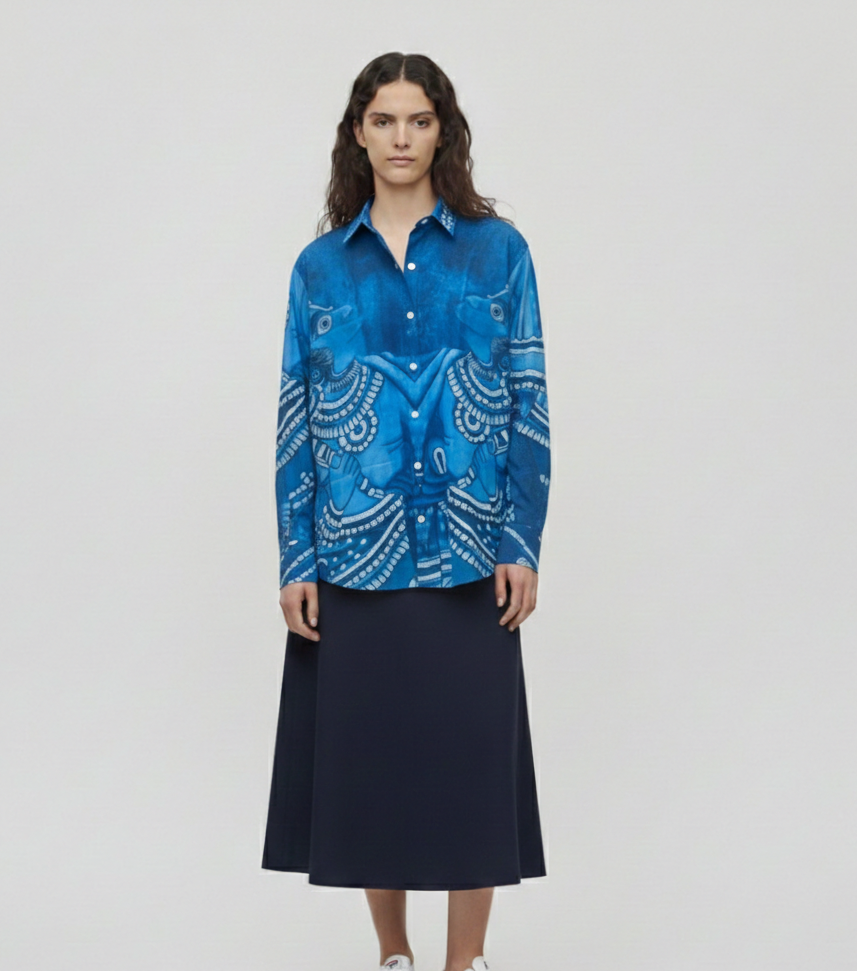 Person wearing a blue patterned shirt and navy skirt on a white background