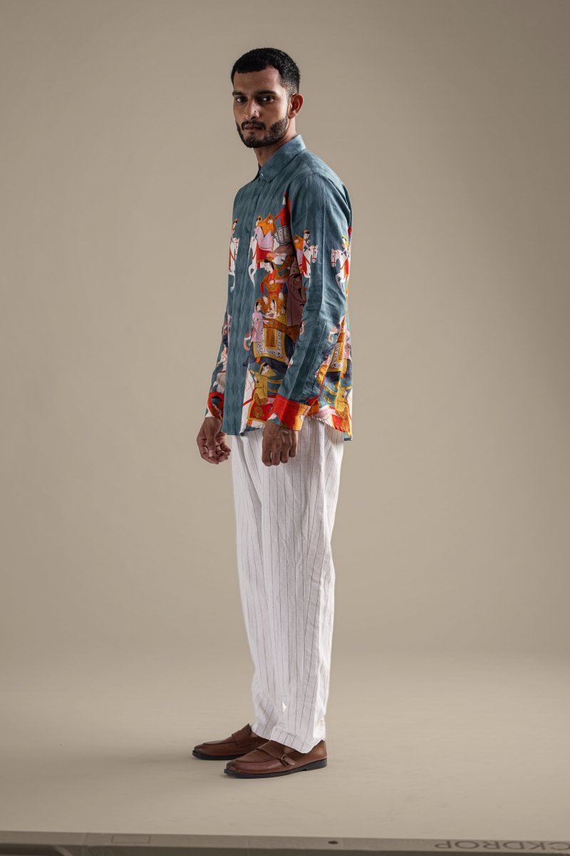 Man wearing the Kirtharjuna shirt with white trousers, full length side view