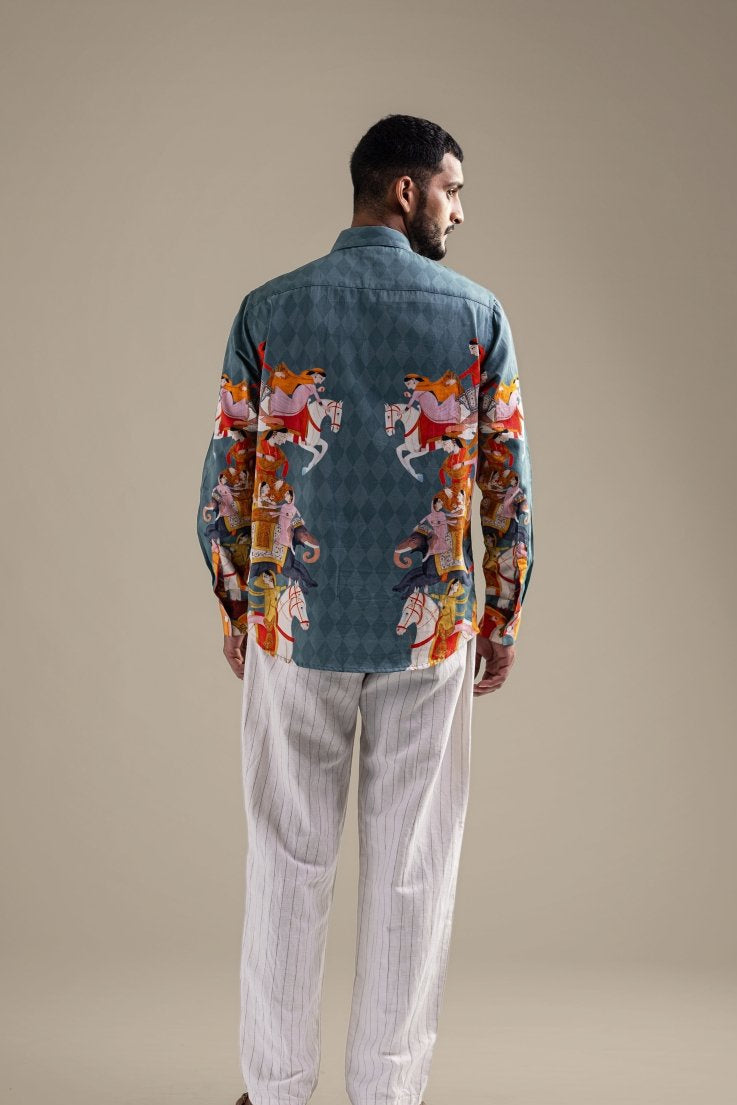 Man wearing the blue Kirtharjuna shirt, back view, looking to the side