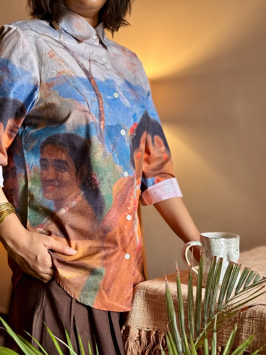 Close view of the Shakuntala shirt on a woman standing beside a table, hand on the front