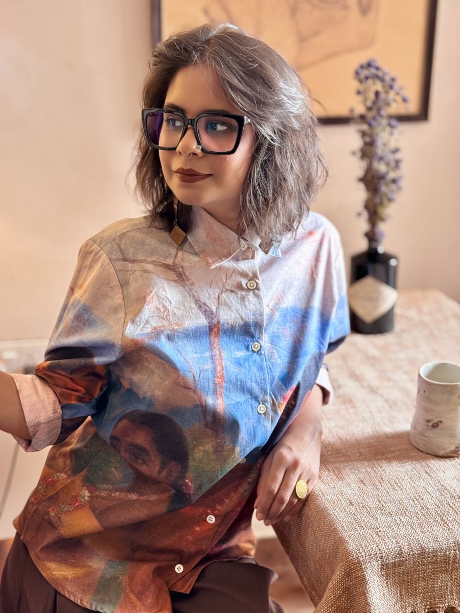 Woman wearing the Shakuntala shirt, seated at a table, looking to the side